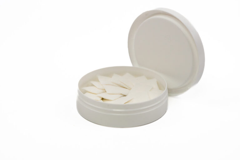 Nicotine pouches in an open white container displayed on a white background as a product photo
